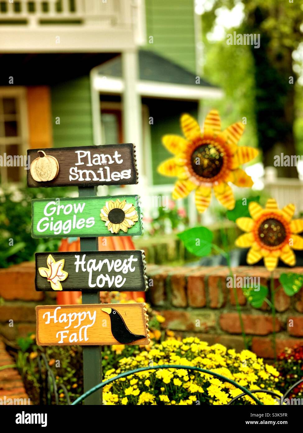 Ein Außenschild in einem Innenhof mit fröhlichen und lustigen Zitaten. Handbemalt auf Holz mit bunten Oktober- und Herbstfarben. Stockfoto