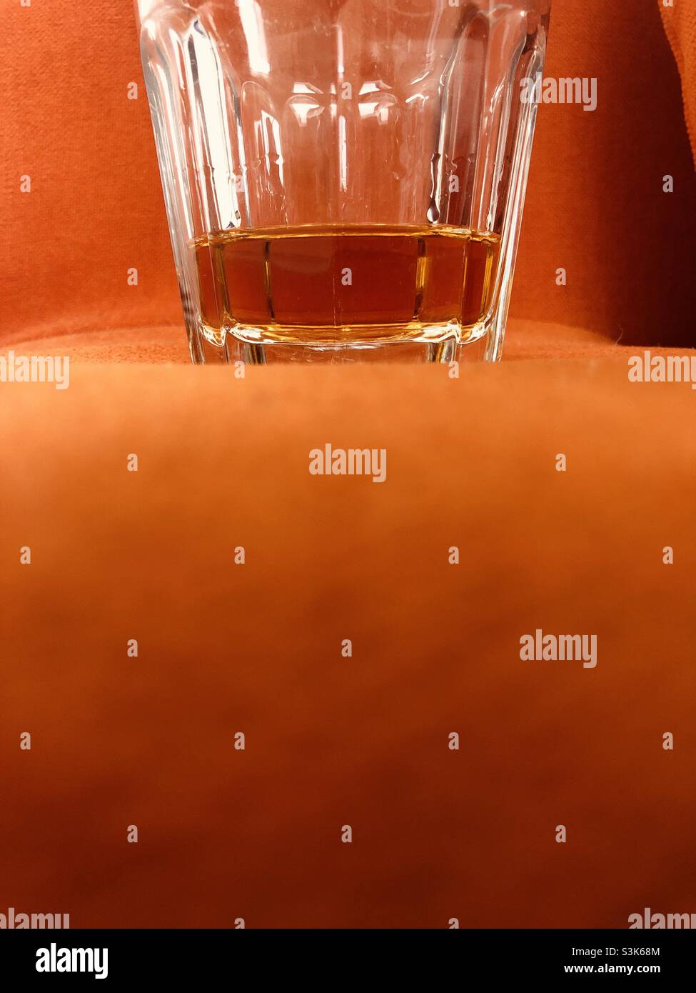 Glas Whisky auf einer orangefarbenen Oberfläche mit viel Platz für Text - Smartphone-aufgenommenes Stockfoto
