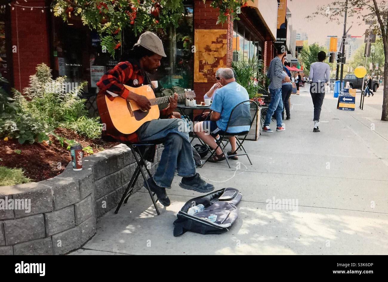 Street Photography, Kensington in Calgary, Alberta , Entertainer, Busker, Musiker, Gitarrist, Sänger , Gitarrenkoffer, Bargeld, Geld - Smartphone-aufgenommenes Stockfoto