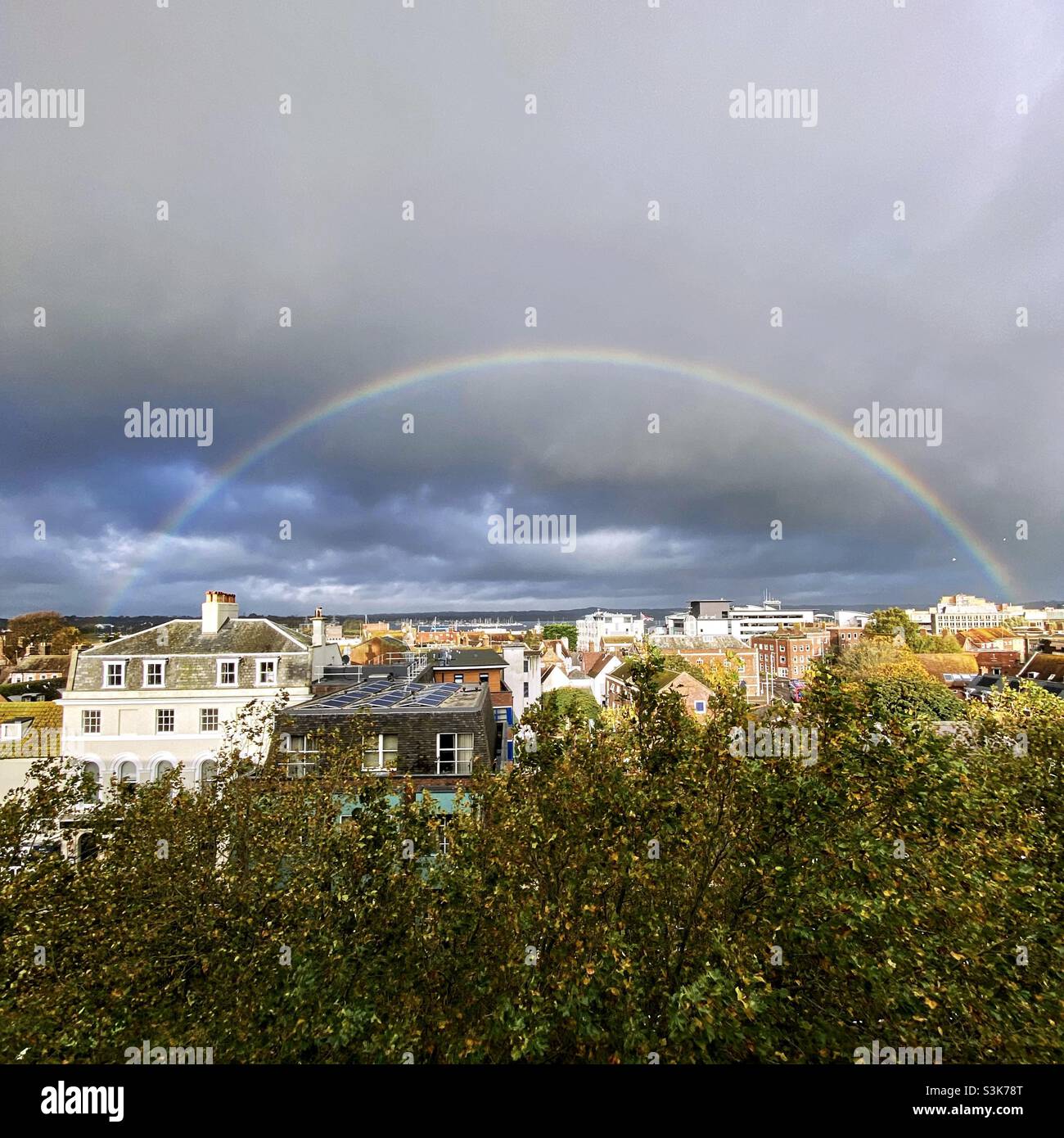 Wetter in Großbritannien: Ein Regenbogen leuchtet während eines kurzen morgendlichen Regensturms über den Häusern von Poole Town. Poole, Dorset, England, Großbritannien. Stockfoto