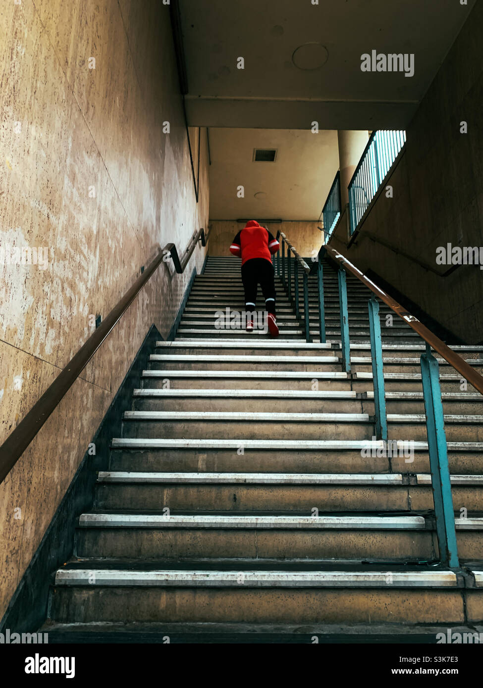 Ein Mann mit einem roten Oberteil, der eine Treppe hinauf ging Stockfoto