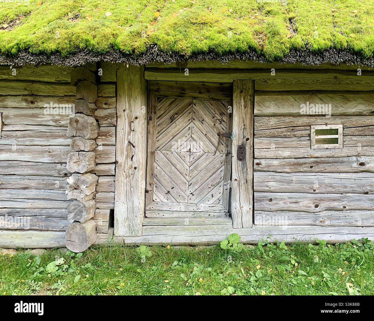 Altes Blockhaus mit Eingangstüren und moosigen Dach - Smartphone-aufgenommenes Stockfoto