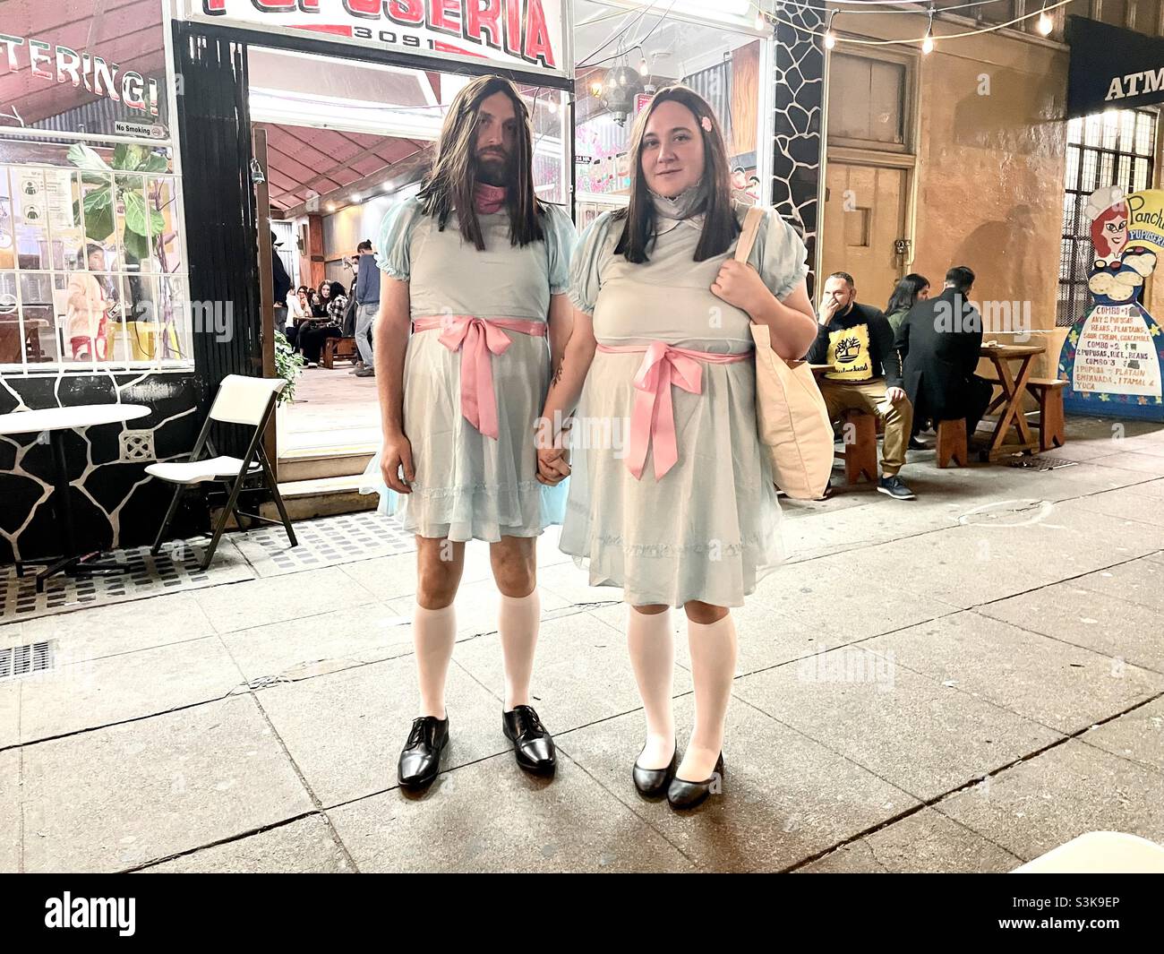 Halloween im Mission District, San Francisco. Ein Paar verkleidet als die Alptraum gruseligen Zwillinge in The Shining. Stockfoto