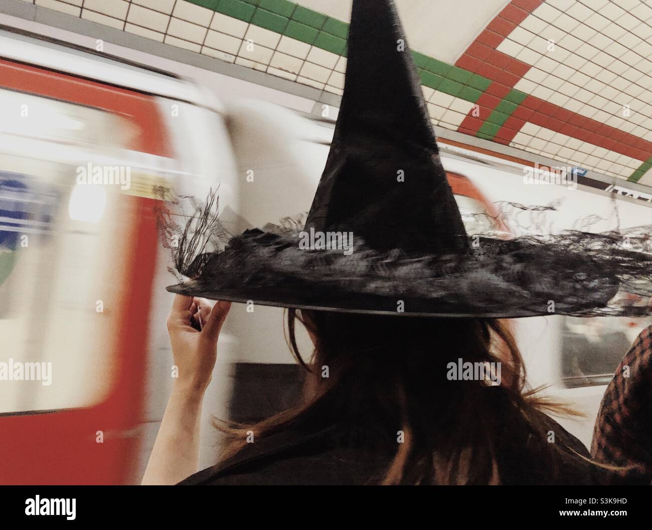 Frau wartet auf U-Bahnstationen, als sie sich als Hexe für Halloween kleidete - Smartphone-aufgenommenes Stockfoto
