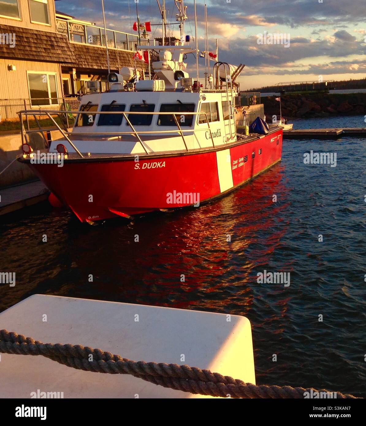 Ein kleines Schiff der kanadischen Küstenwache, das am lokalen Hafen nahe dem Sonnenuntergang vor Anker liegt Stockfoto