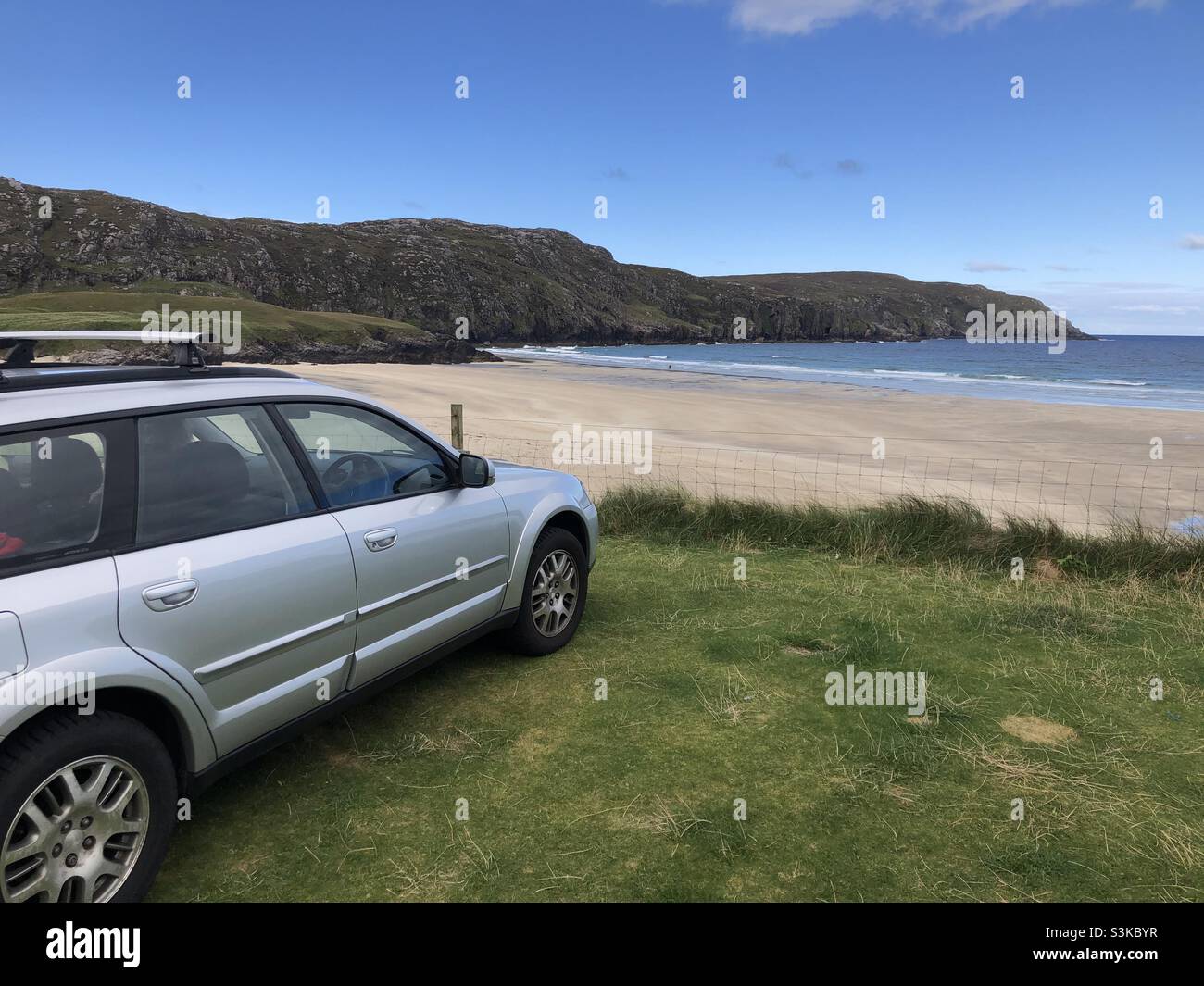 Auf dem Rasen mit Blick auf einen Strand auf Lewis in Schottland steht ein Kombi-Auto Stockfoto
