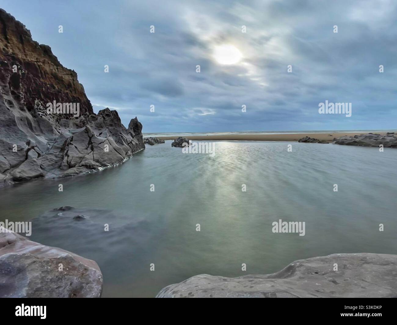 Schwache Wintersonne über einem Felsenpool am Strand von Mewslade, Gower, Südwesten von Wales, November. Stockfoto