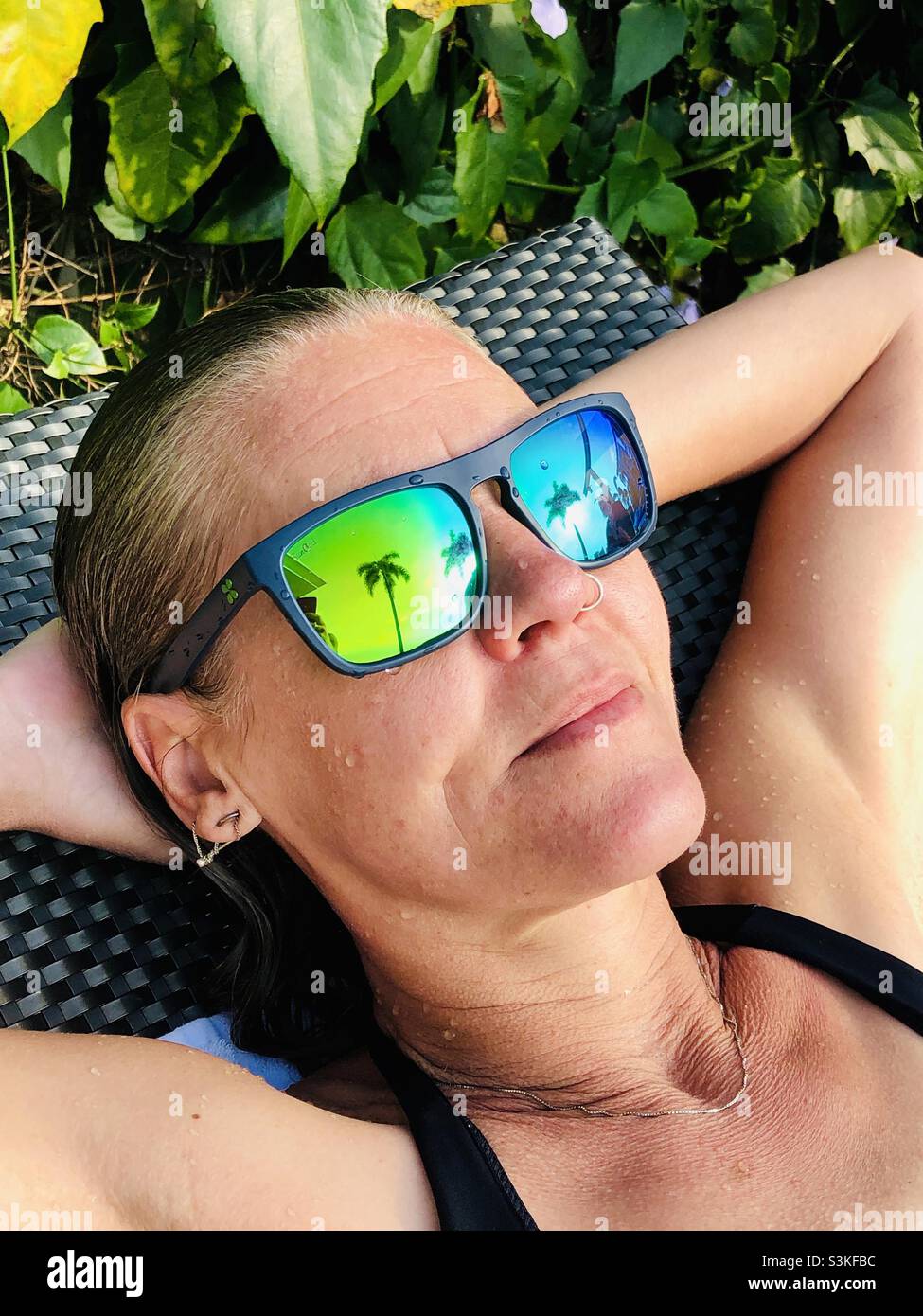 Eine Frau in reflektierender Sonnenbrille entspannt sich im Sonnenschein Stockfoto