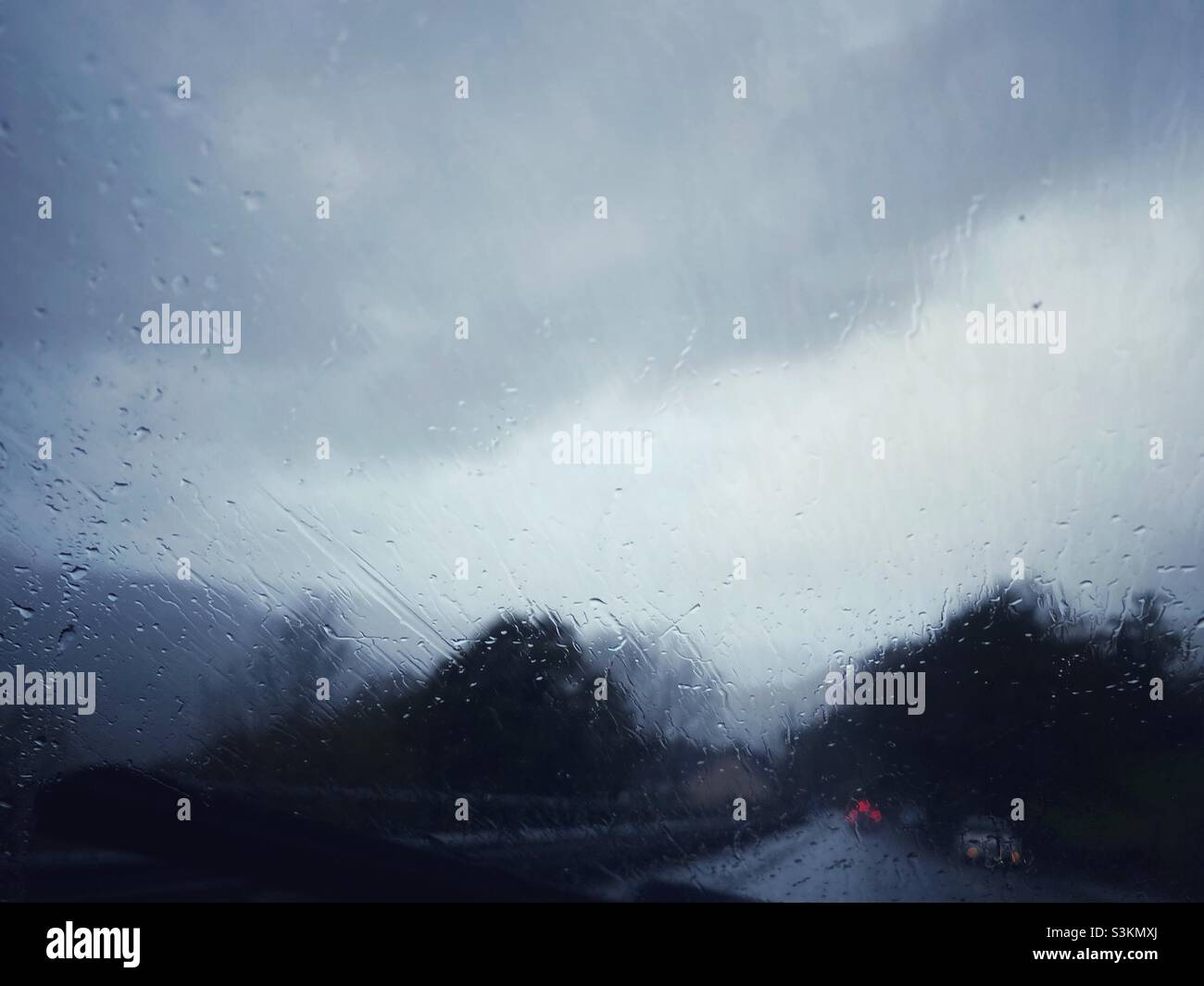 Ein Foto an einem regnerischen Tag, das aus einem Auto heraus aufgenommen wurde. Reisen bei schlechtem Wetter - Smartphone-aufgenommenes Stockfoto