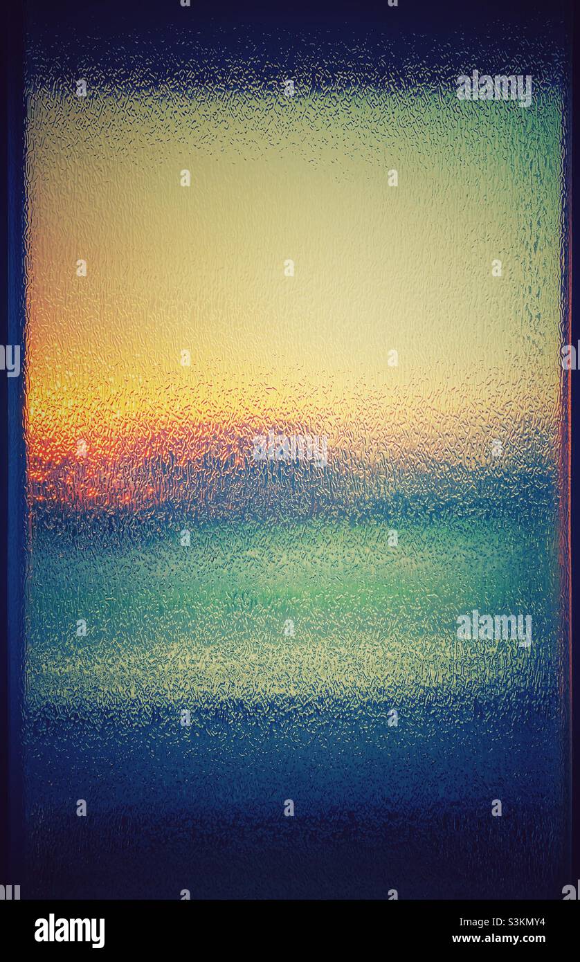 Ein Sonnenaufgang durch eine Glastür. Abstrakte Wirkung des Sonnenlichts und schöne Farben - Smartphone-aufgenommenes Stockfoto