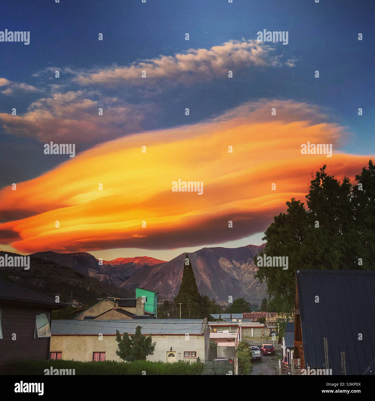 Eine geschichtete Wolke, die von der untergehenden Sonne hinter der cordillera in Esquel, Patagonien, Argentinien, erleuchtet wird. - Smartphone-aufgenommenes Stockfoto