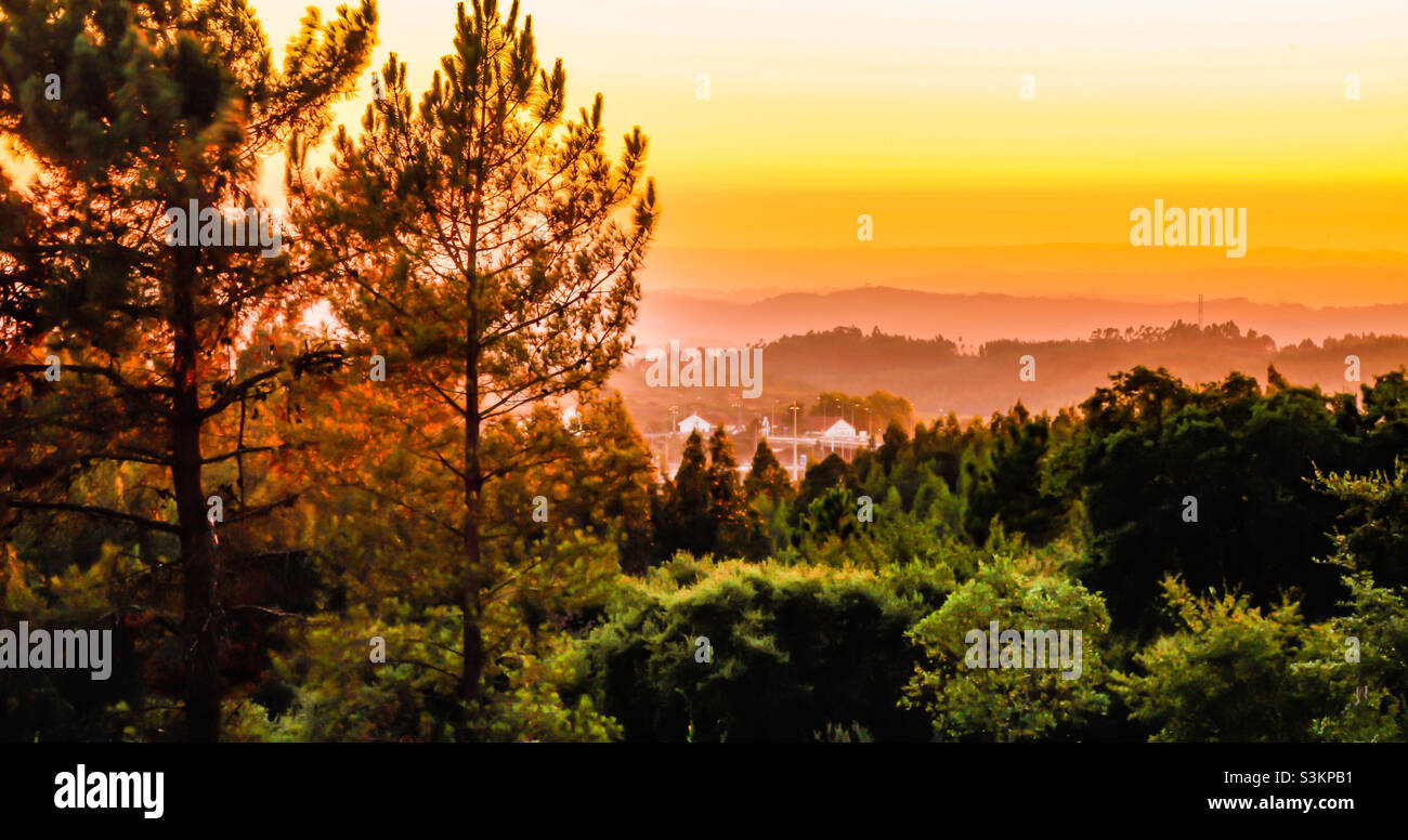 Spätsommeruntergang über von Bäumen bedeckten Hügeln und Dörfern in Zentralportugal Stockfoto