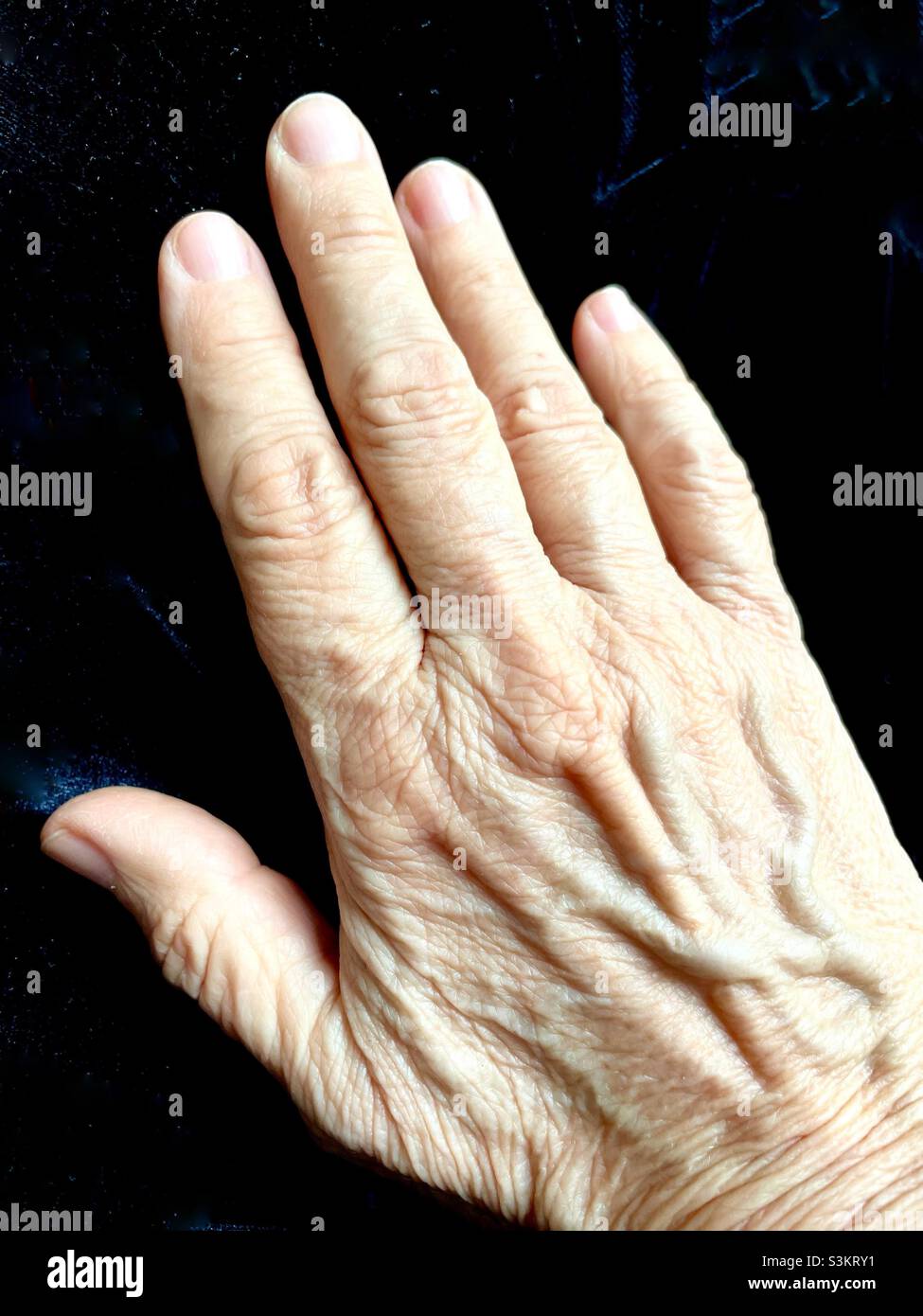 Porträt einer rechten Hand auf schwarzem Hintergrund - Smartphone-aufgenommenes Stockfoto