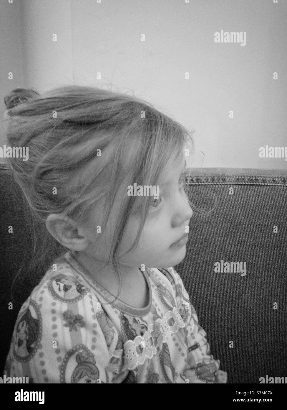 Schwarz-weißes Seitenportrait eines kleinen Mädchens mit den Haaren in einem Brötchen Stockfoto