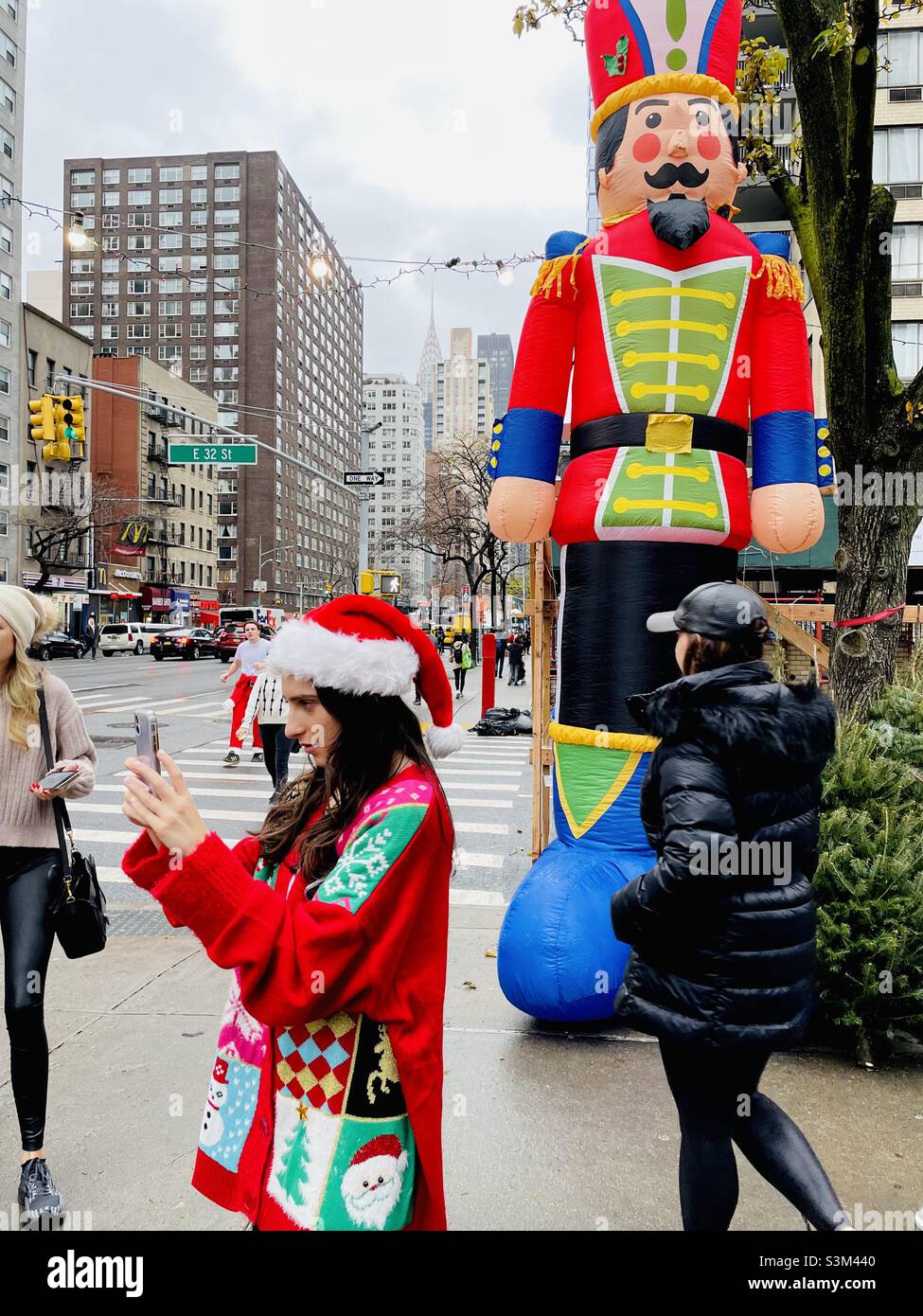 Frau in leuchtendem Rot Weihnachten für ein Selfie in New York City - Smartphone-aufgenommenes Stockfoto