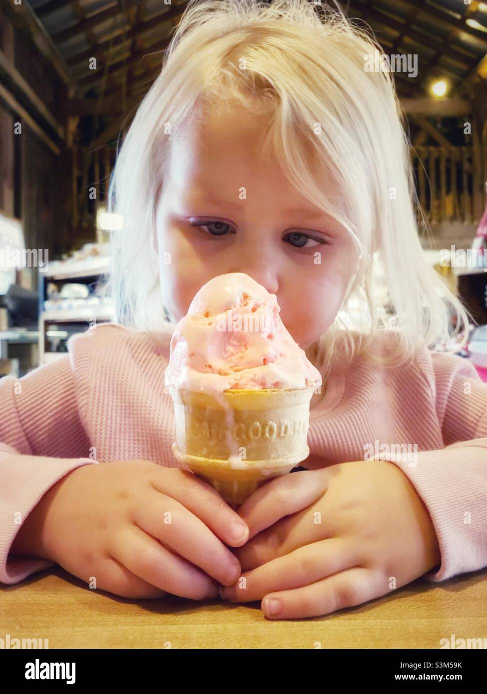 Ein kleines Mädchen, das einen Eiskegel anmute. Stockfoto
