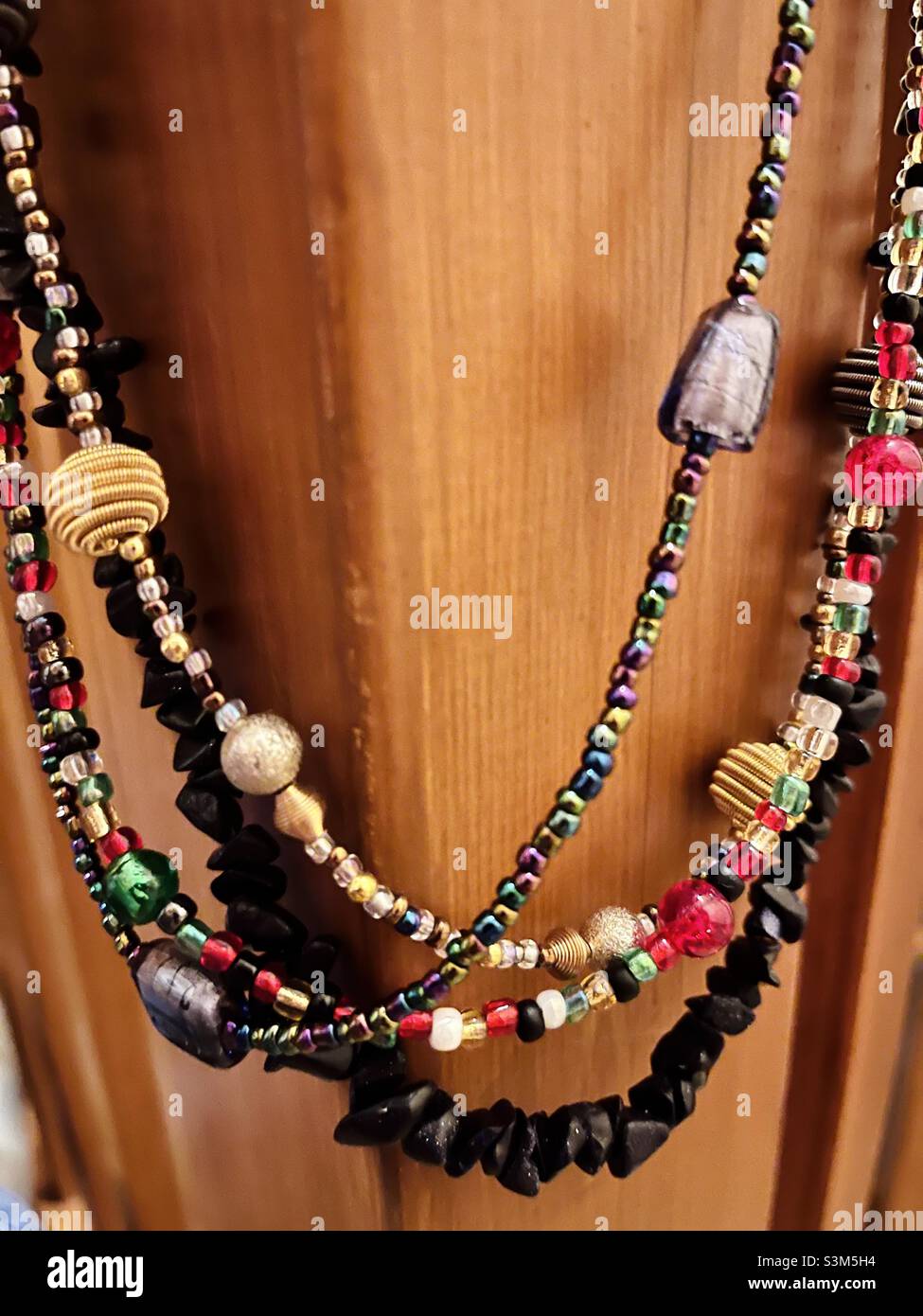 Mehrfarbige Perlen-Halsketten auf einem Holzpfosten Stockfoto