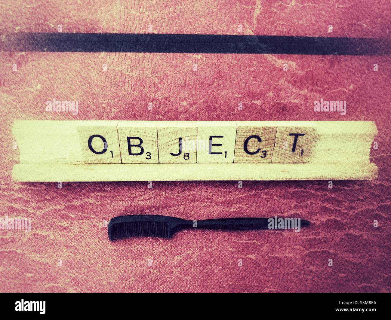 Scrabble Wortobjekt vor dunkelrosa Hintergrund in Grunge. Und Augenbrauen kleinen Kamm. Stockfoto
