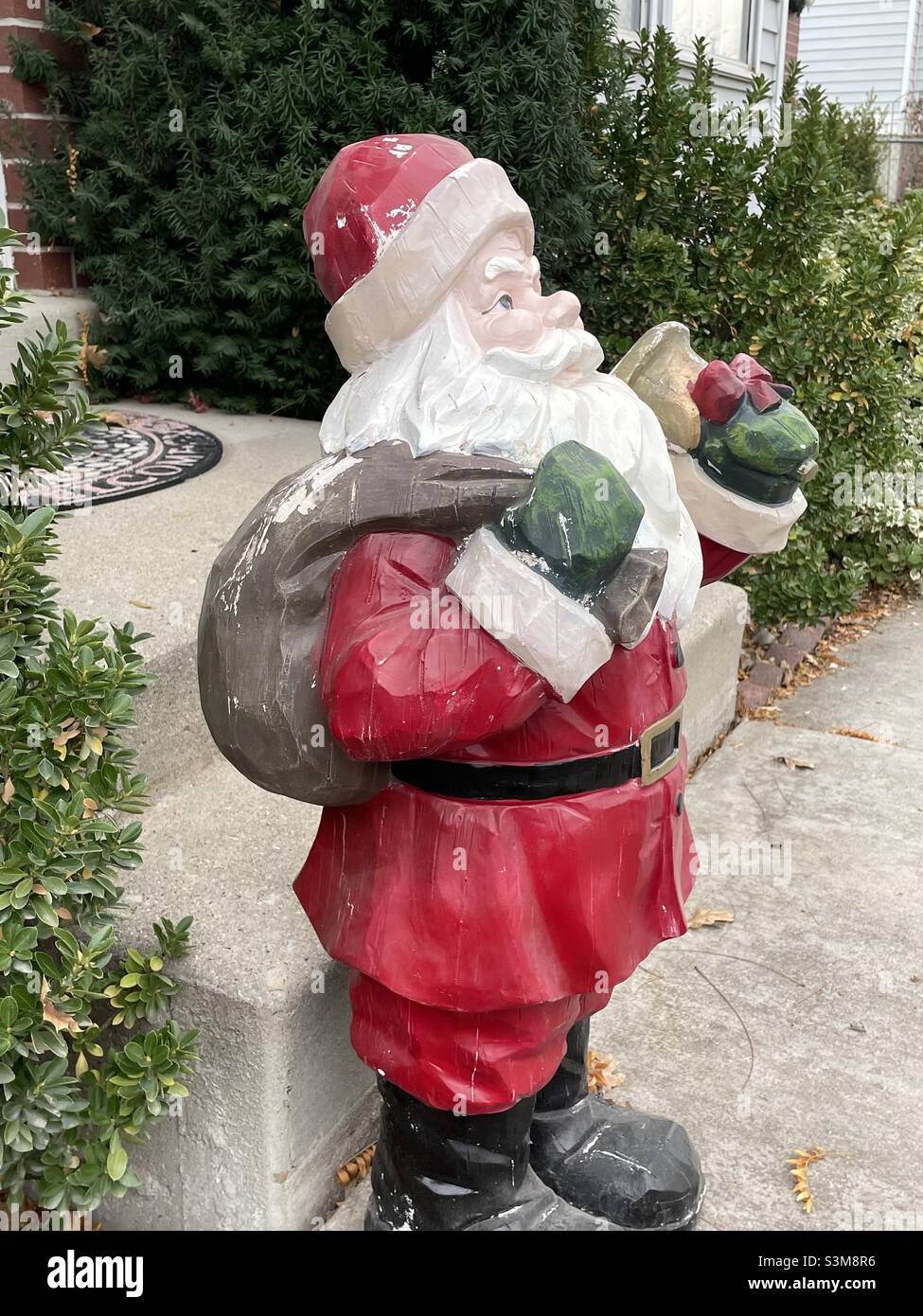 Ein traditioneller, rot getragener Weihnachtsmann sitzt während der Weihnachtszeit in Utah, USA, vor einem Haus. Stockfoto