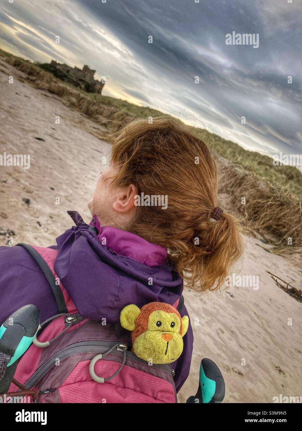 Frau, die am Strand von Bamburgh Castle in Northumberland spazieren geht Stockfoto