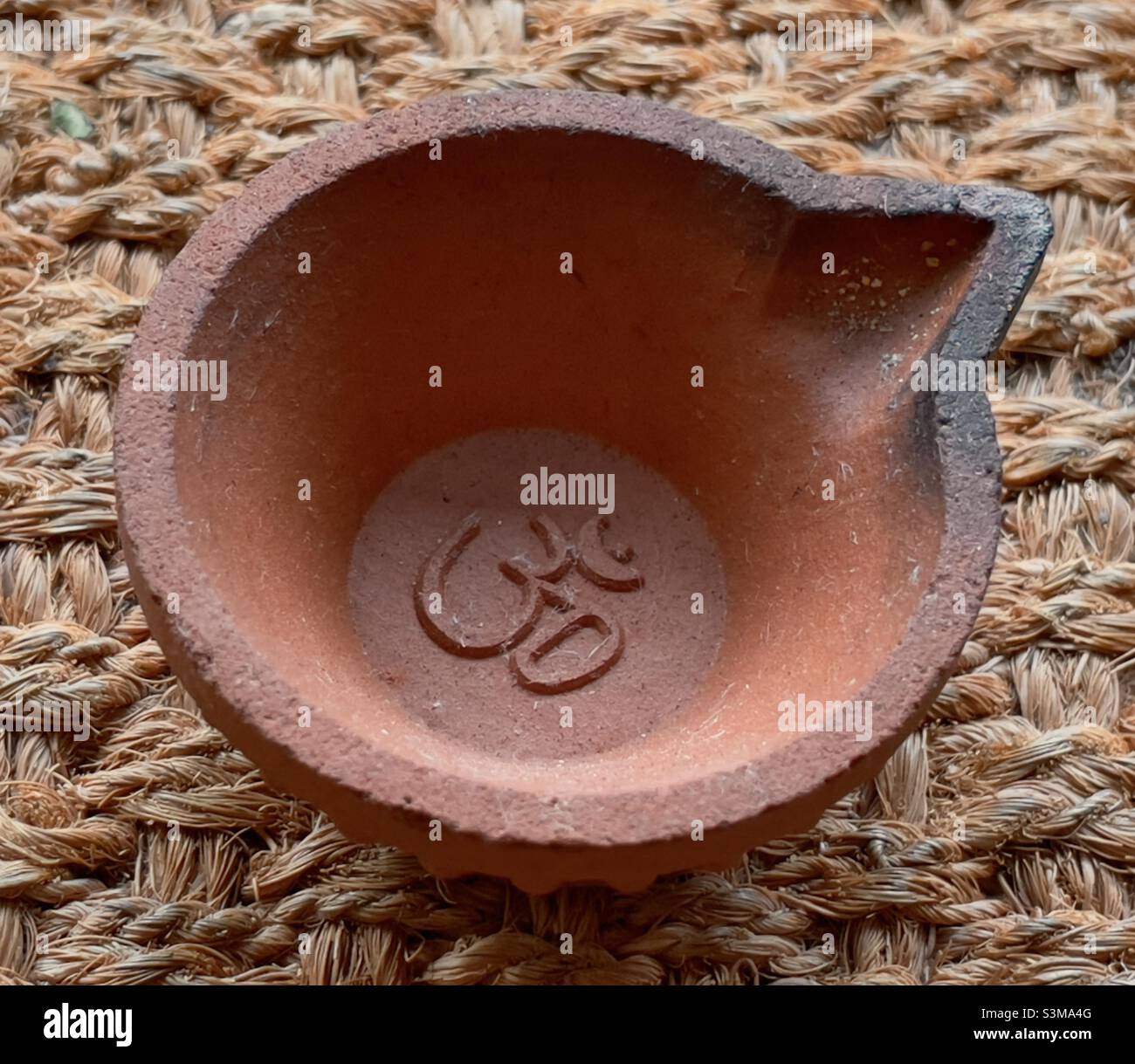 Eine in Massen produzierte Terrakotta-Lampe mit einem eingeprägten Zeichen „Om“ zur Verwendung als Votivopfer in einem Hindu-Tempel - Smartphone-aufgenommenes Stockfoto Eine in Massen produzierte Terrakotta-Lampe mit einem eingeprägten Zeichen „Om“ zur Verwendung als Votivopfer in einem Hindu-Tempel - Smartphone-aufgenommenes Stockfoto
