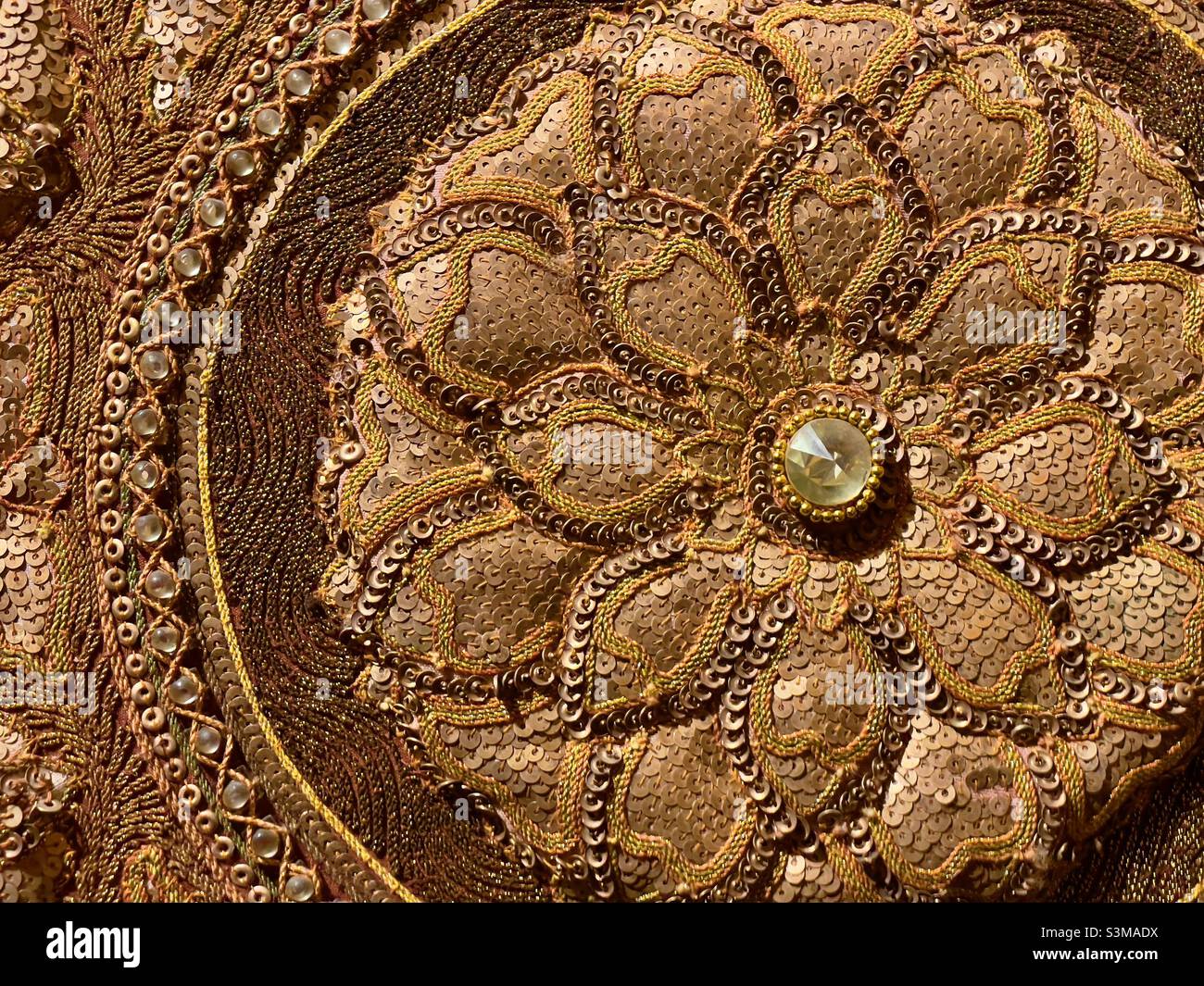 Ein kreisförmiges Detail aus einer traditionellen burmesischen Stickerei, dreidimensional und mit Schmuck verziert - Smartphone-aufgenommenes Stockfoto