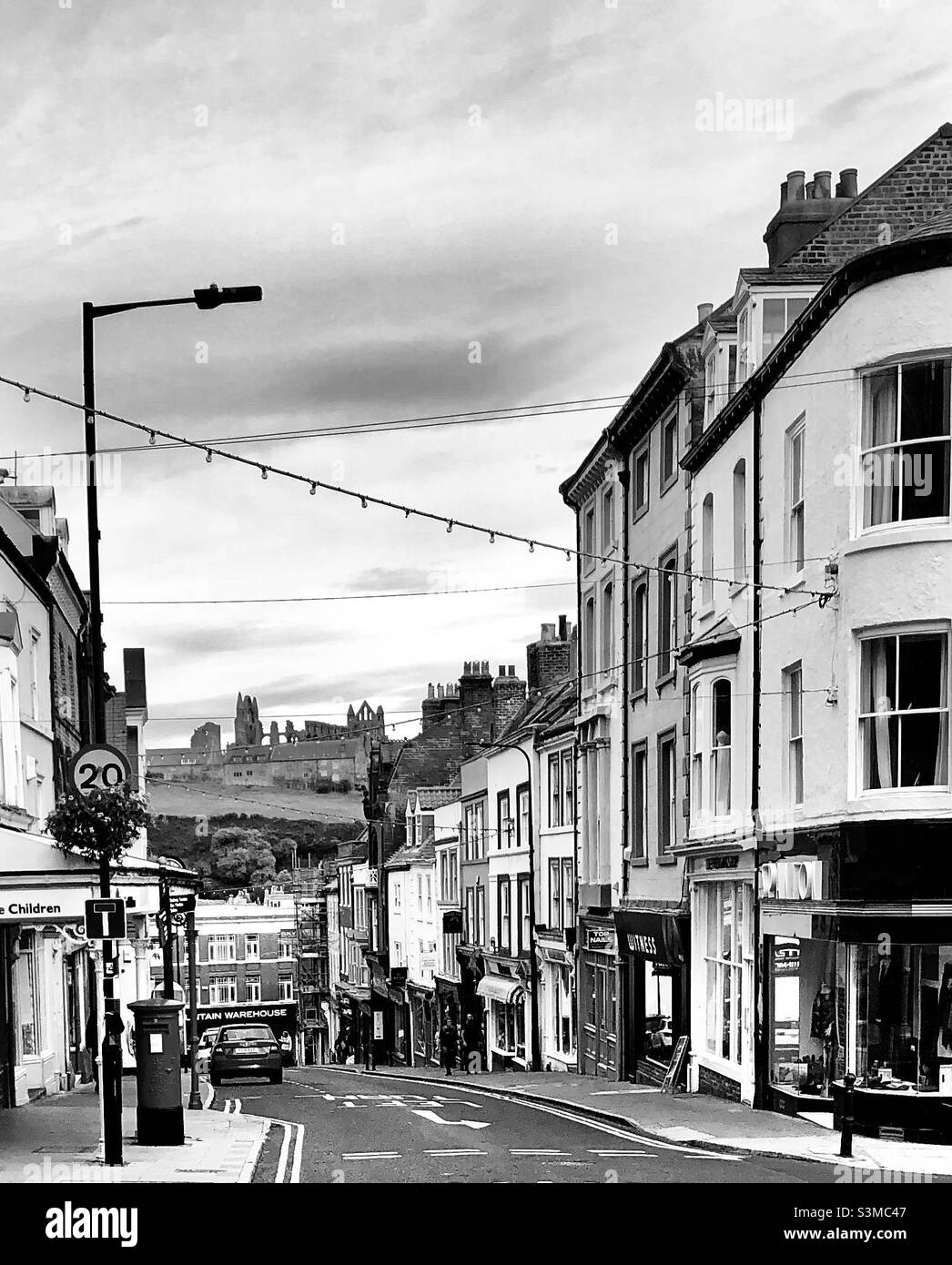 Schwarz-Weiß-Ansicht der Whitby Street mit Whitby-Abtei im Hintergrund, traditionelles britisches Stadtbild und Schauplatz des gotischen Romans Dracula von Bram Stoker Stockfoto