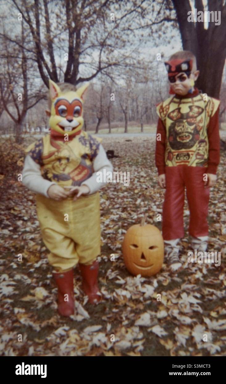Halloween 1960s Amerika oder Trick or Treat, wie es genannt wurde. Zwei kleine Jungen mit einem Kürbis in einem Wald im Herbst/Herbst Stockfoto