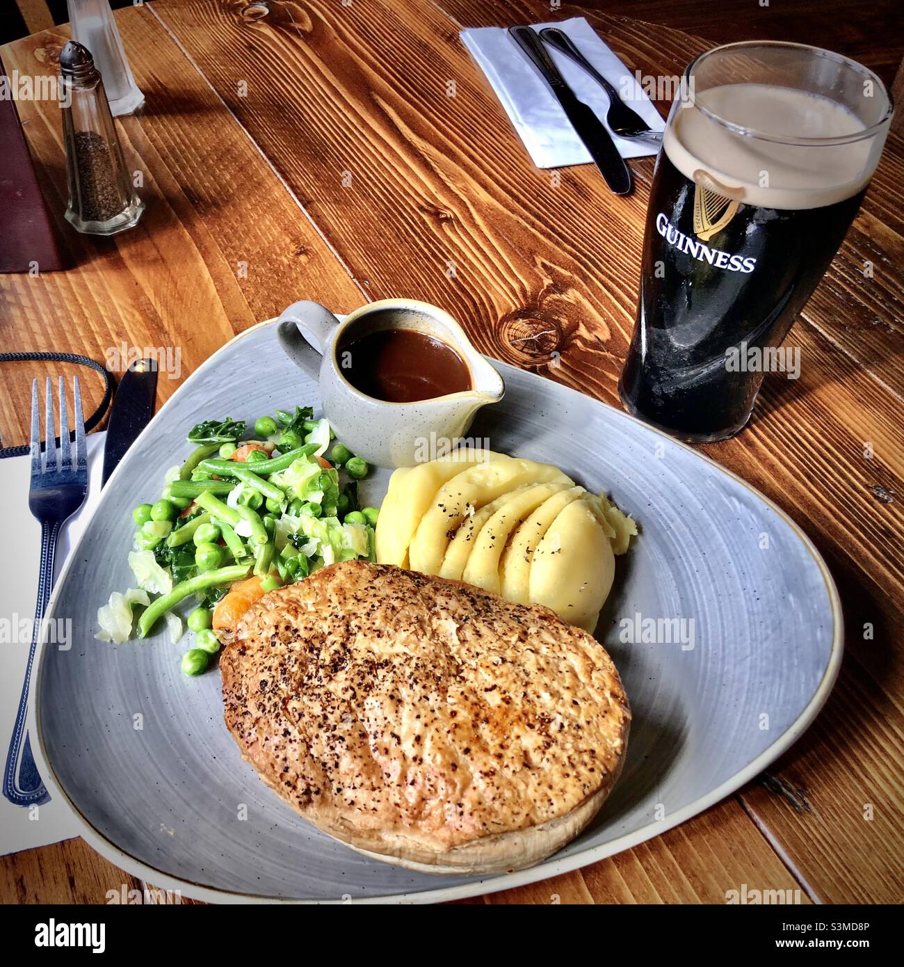 Fleischpastete mit Gemüse, Kartoffeln und einem Pint guinness, typisch britisches Pub-Essen - Smartphone-aufgenommenes Stockfoto
