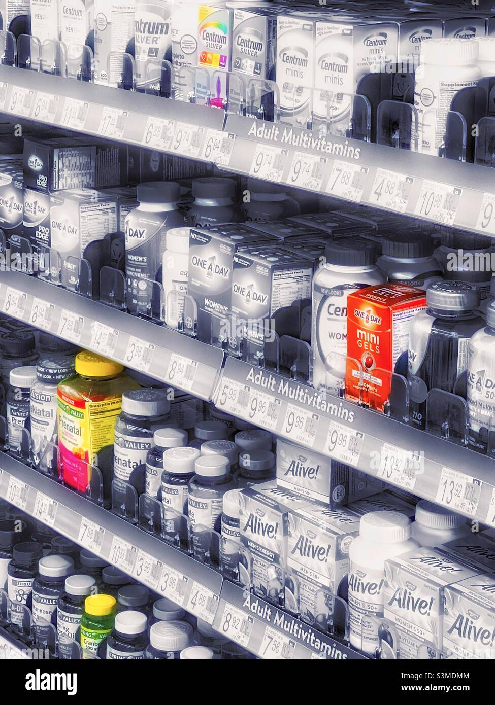 Vitamine, Mineralstoffe und Nahrungsergänzungsmittel in den Regalen eines lokalen Walmart in Utah, USA. Die meisten Produkte sind in einem silberfarbenen Schwarz-Weiß, aber ausgewählte Farbe wurde auch für künstlerische Wirkung verwendet. - Smartphone-aufgenommenes Stockfoto