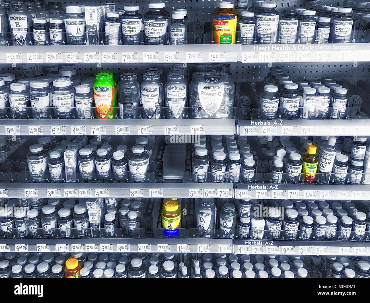 Vitamine, Mineralstoffe und Nahrungsergänzungsmittel in den Regalen eines lokalen Walmart in Utah, USA. Die meisten Produkte sind in einem silberfarbenen Schwarz-Weiß, aber ausgewählte Farbe wurde auch für künstlerische Wirkung verwendet. - Smartphone-aufgenommenes Stockfoto