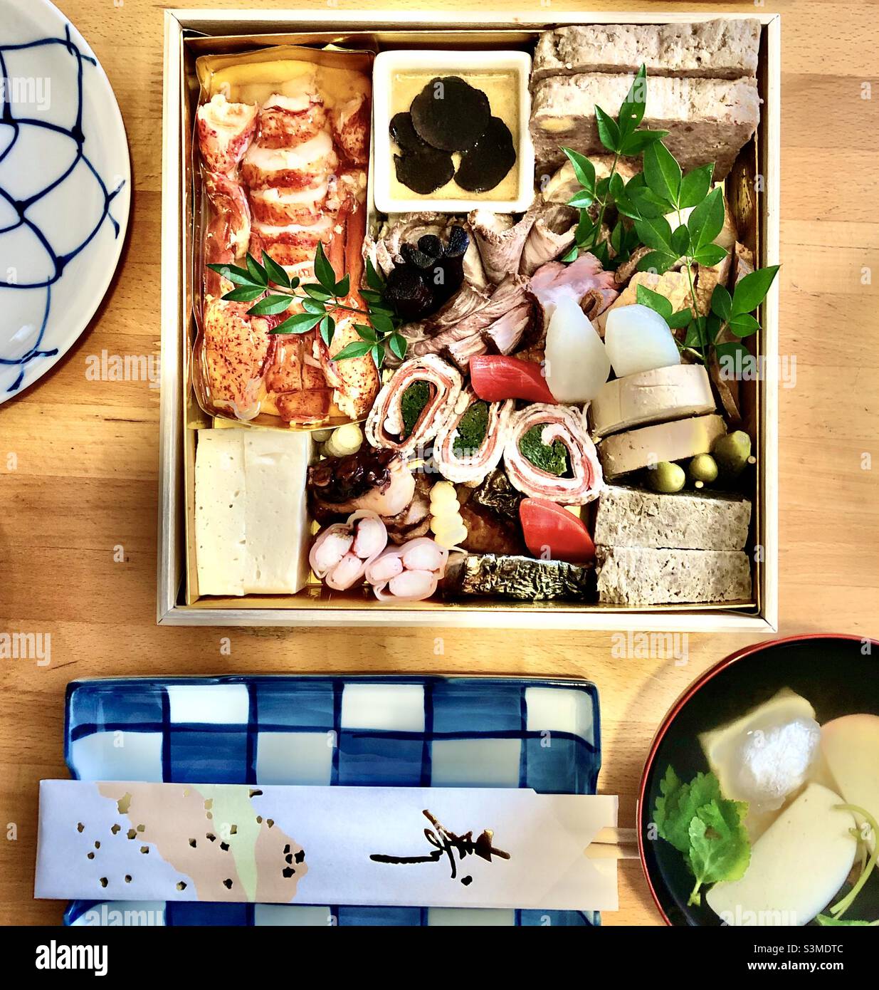 Japanisches Neujahr: Osechi-Box mit Hummer und Hackbraten mit Ozoni-Suppe - Smartphone-aufgenommenes Stockfoto