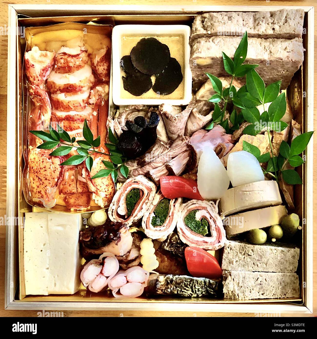 Japanische Osechi-Box, traditionelle Speisen für das neue Jahr, bestehend aus Hummer, Aufschnitt, Schalentieren und eingelegtem Gemüse - Smartphone-aufgenommenes Stockfoto