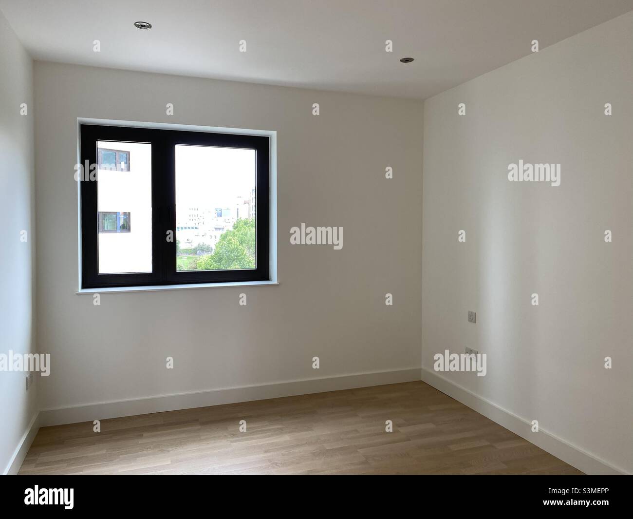 Leeres Schlafzimmer mit einem quadratischen Fenster und weißen Wänden Stockfoto