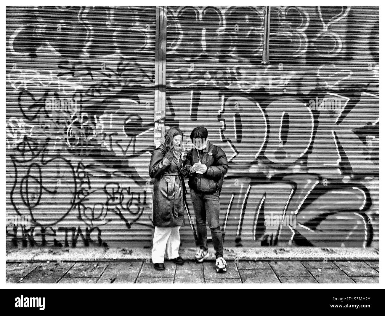 Ein Paar in der Peckham High Street vor Graffiti. - Smartphone-aufgenommenes Stockfoto
