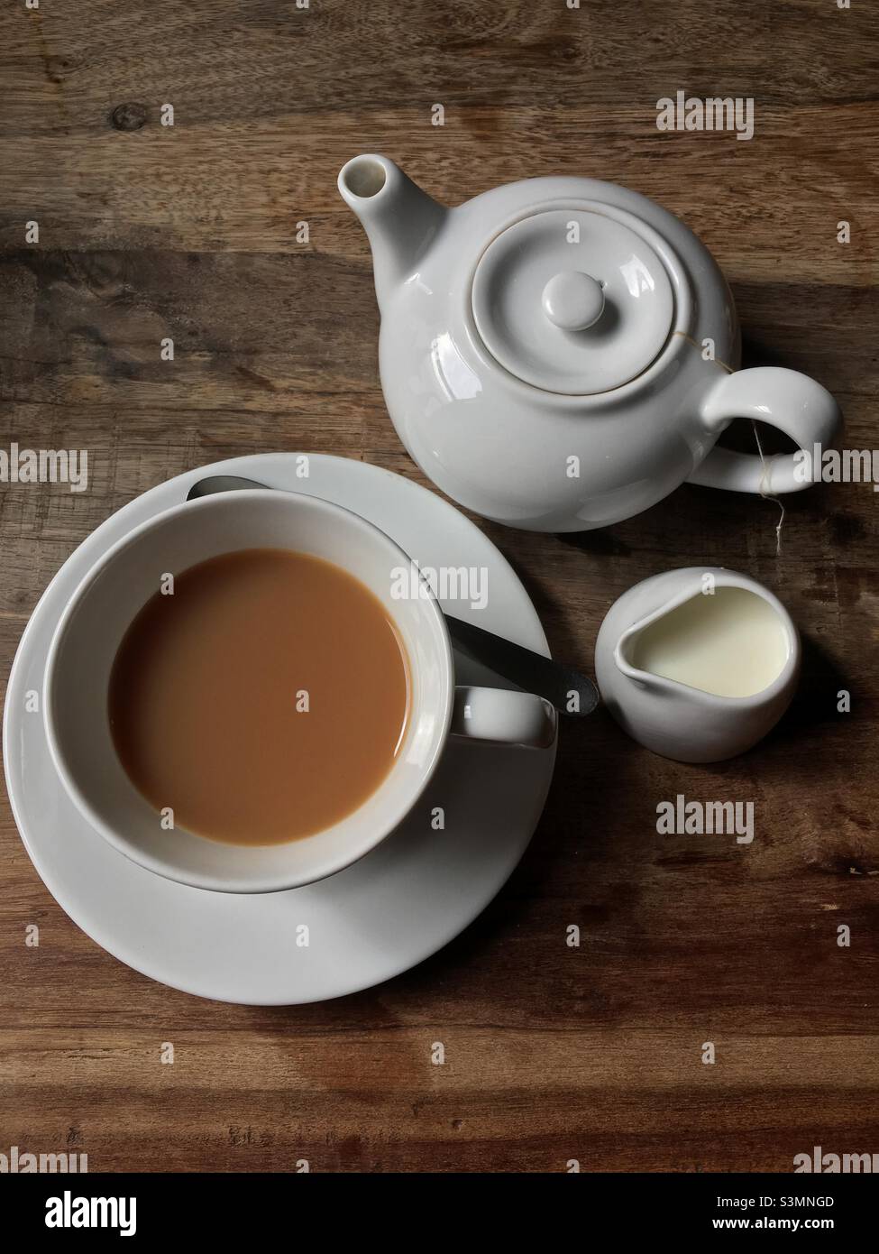 Tasse und Kanne Tee mit Milch auf einem rustikalen Holztisch. Aufgenommen in England Stockfoto