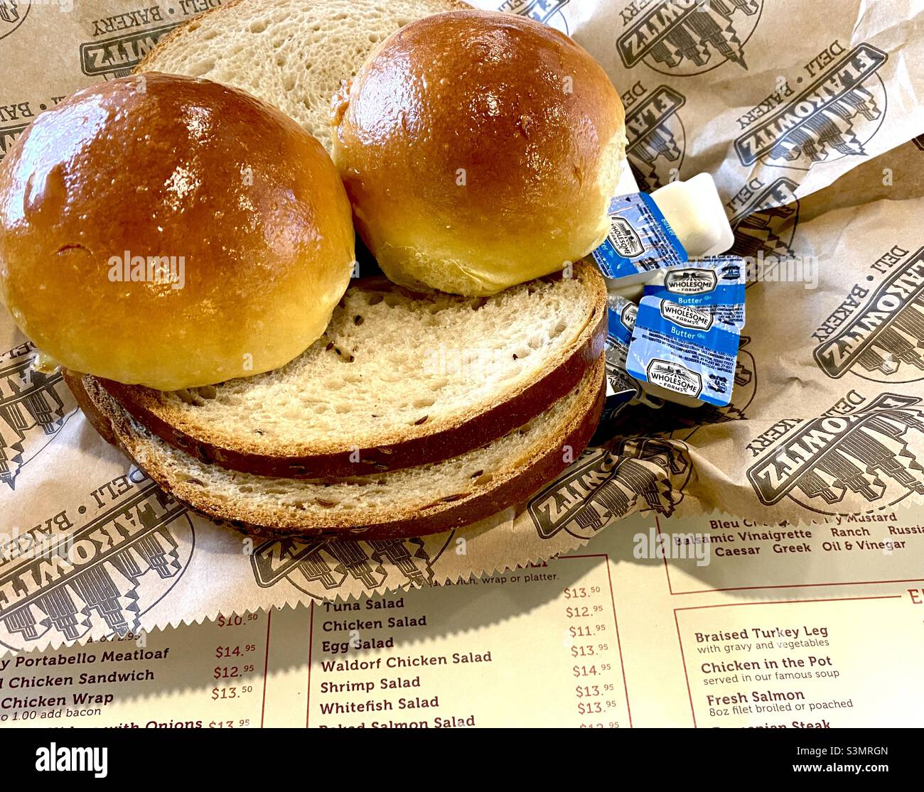Tischfoto von Ryebrot und frischen Brötchen und Butter in einem lokalen jüdischen Delikatessengeschäft namens Flakowitz in Florida. - Smartphone-aufgenommenes Stockfoto