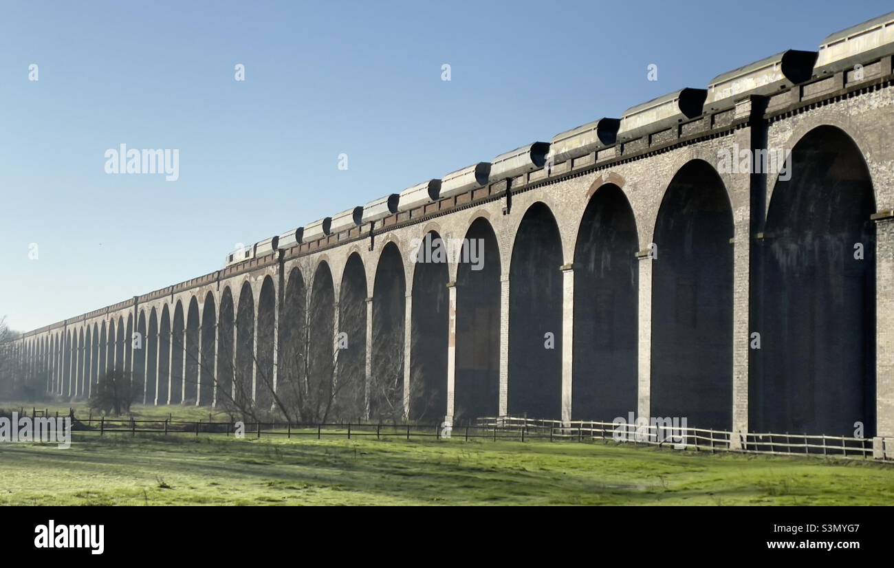 Ein Güterzug, der über den Viadukt von Welland in Northamptonshire fährt, wo er mit der Seaton Road kreuzt Stockfoto