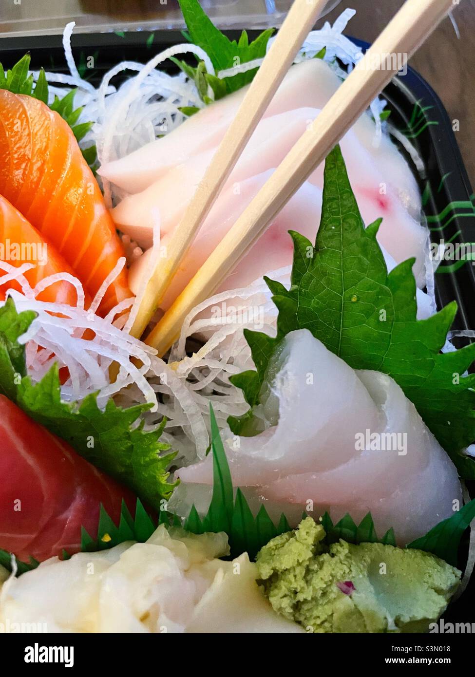 Nahaufnahme eines Lieferkartons mit frischen Sashimi und Essstäbchen, 2022, New York City, USA - Smartphone-aufgenommenes Stockfoto