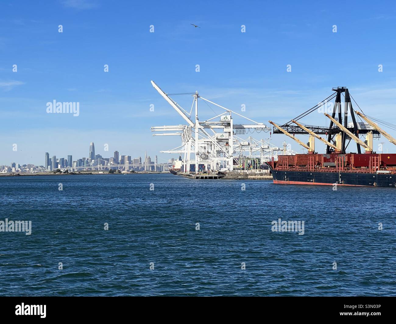 Hafen von Oakland Schiffskräne mit der Skyline von San Francisco. Stockfoto