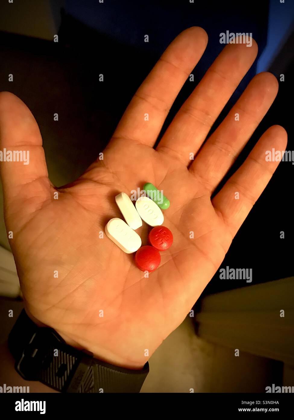 Kaukasische Hand hält Pillen in vielen Farben Stockfoto