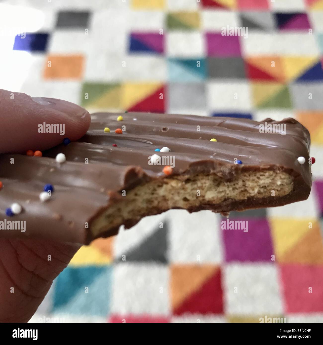 Biss von Schokolade überzogene Cookie mit hellen Teppich Hintergrund Stockfoto