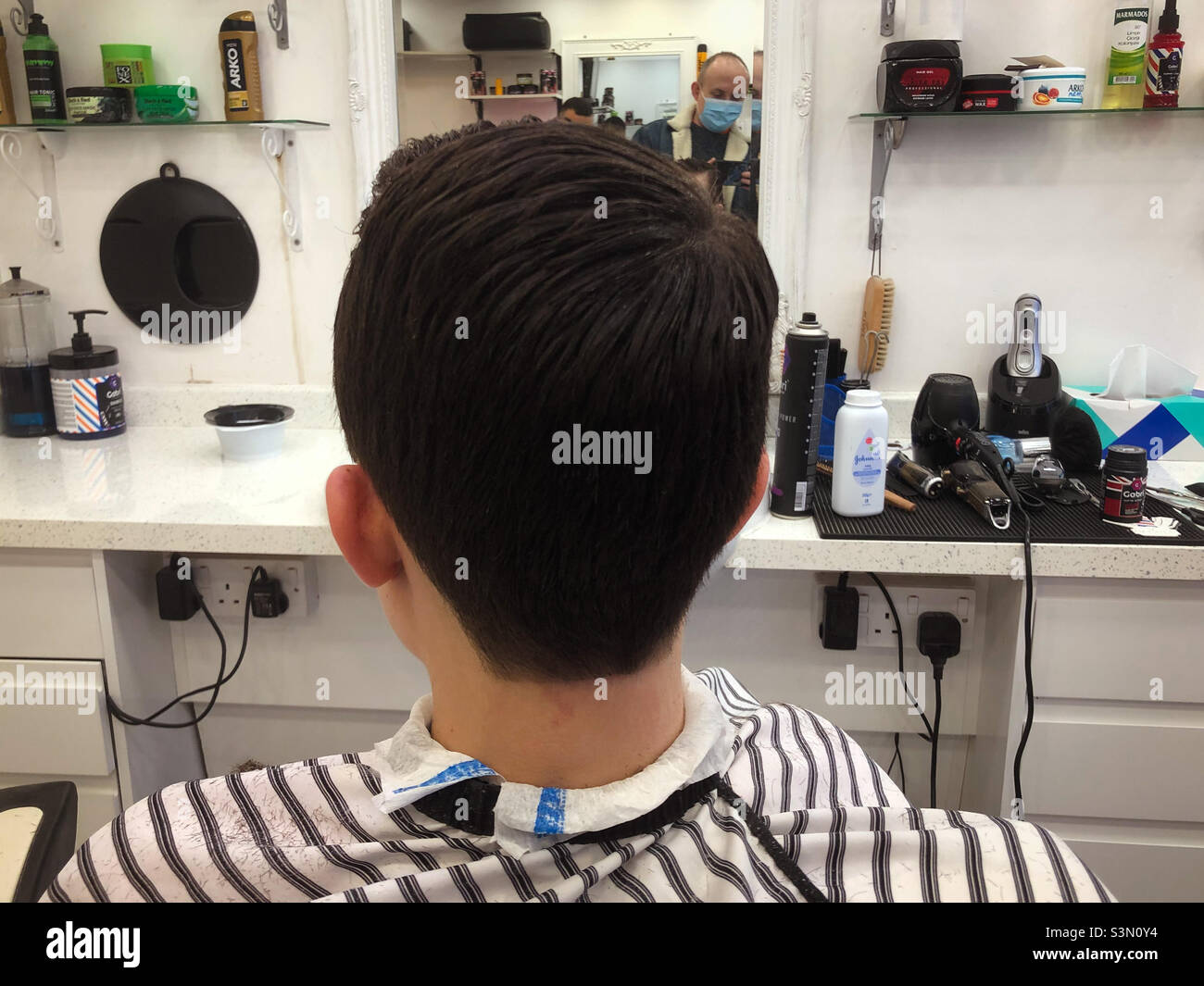 Ein Junge von hinten gesehen saß in einem Friseurladen auf einem Stuhl. Stockfoto