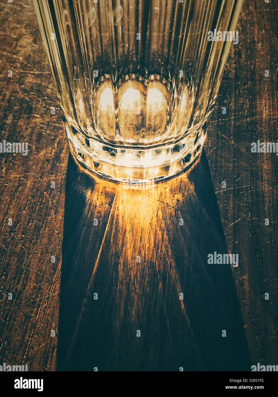 Die Spiegelung eines Glasbechers auf einem Holztisch Stockfoto
