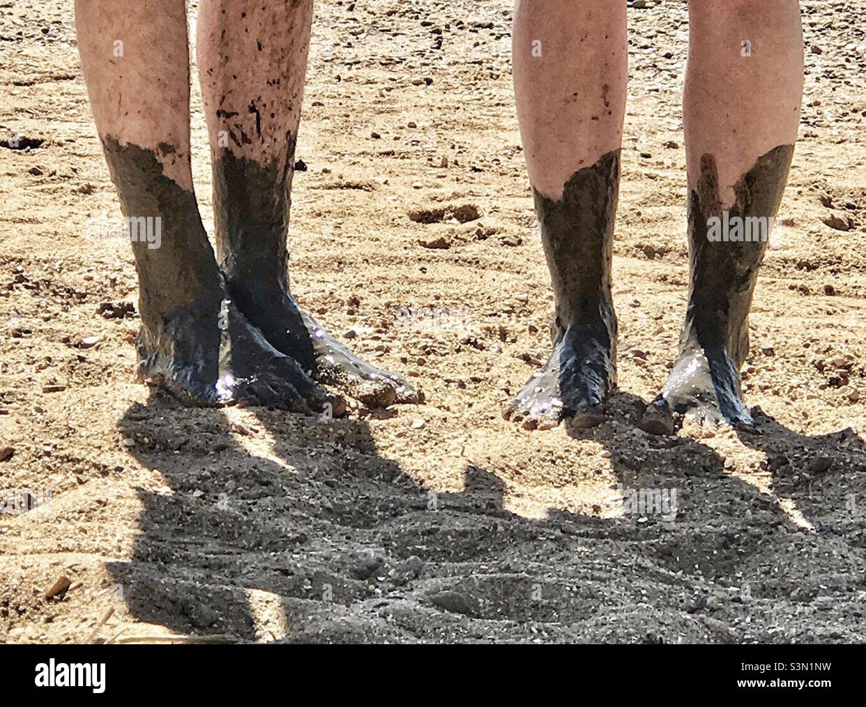 Schlammige Füße - Mann und Frau stehen auf Sand mit schlammigen Füßen vom nahe gelegenen Fluss Stockfoto