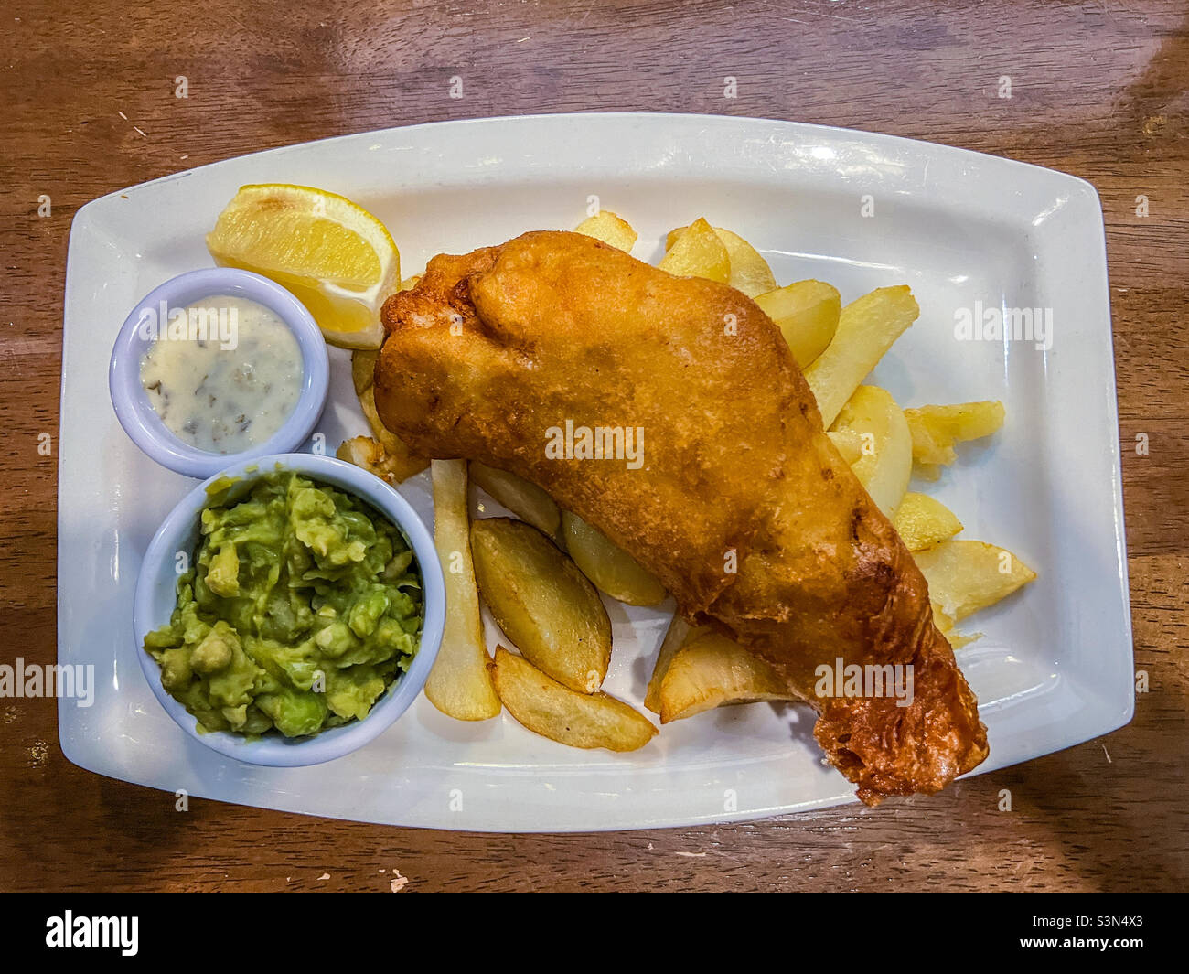 Fisch und Chips mit matschigen Erbsen und Tartaresauce Stockfoto