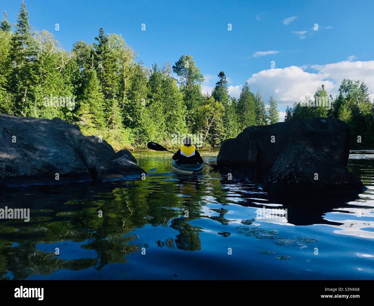 Zwischen zwei Felsen, Kajakfahren an einem kühlen Spätsommertag am Lac Dupuis. Stockfoto