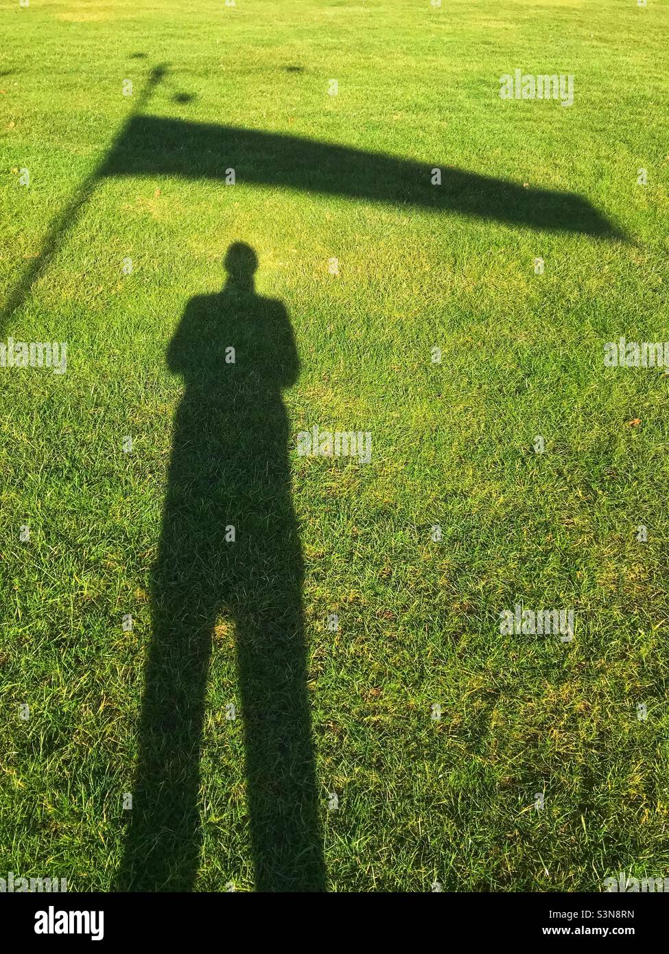 Silhouette eines Mannes, der an einem windigen Tag neben einer Windsocke steht - Smartphone-aufgenommenes Stockfoto