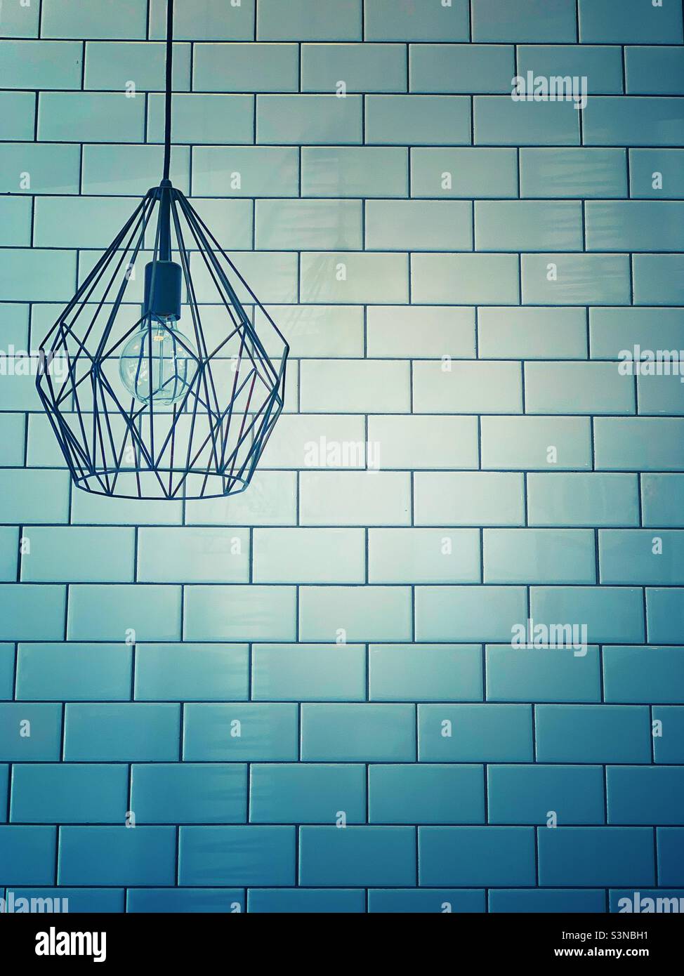 Industrielampe mit gefliester Hintergrundwand Stockfoto
