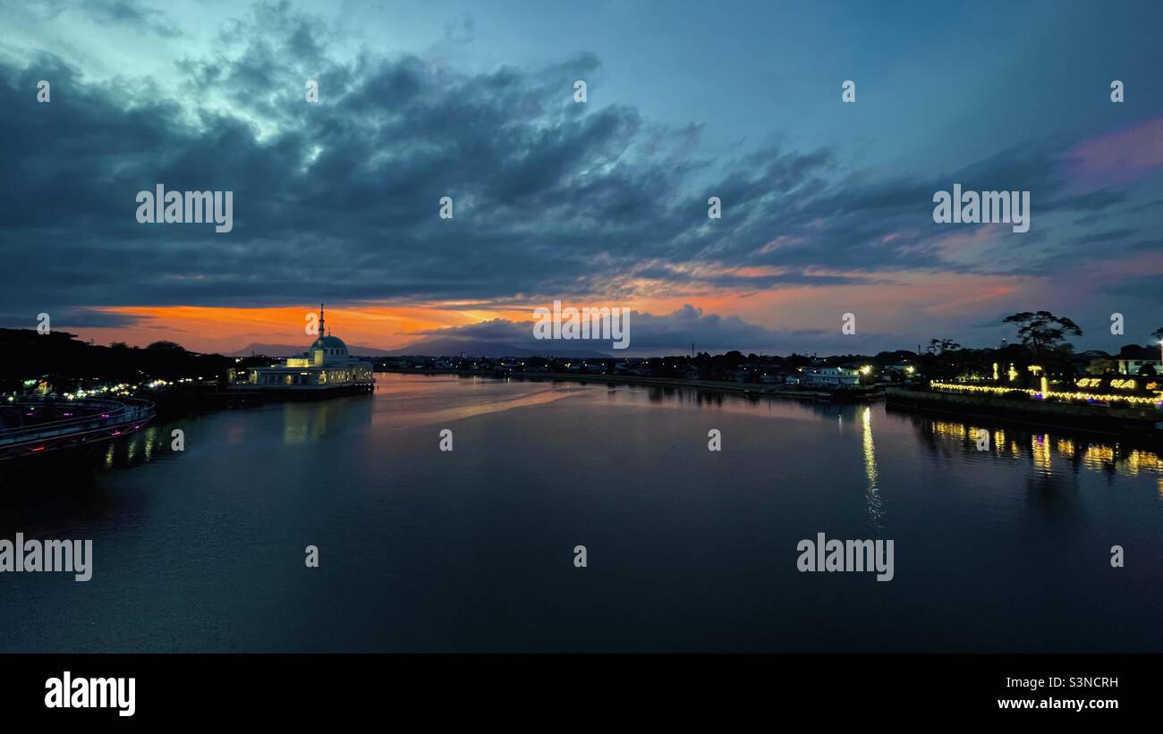 Sungai Sarawak in der Abenddämmerung mit Masjid Jamek und Boyan Village als Hintergrund. Stockfoto